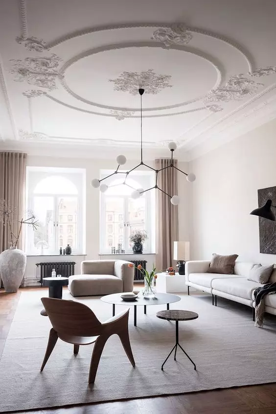 an airy Scandinavian living room with a stucco ceiling, neutral seating furniture, round tables and a chair, a chic chandelier