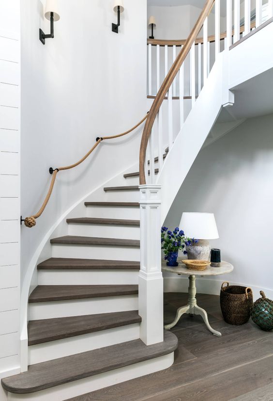 an elegant rounded staircase with rope railing and wooden railing looks very chic and stylish