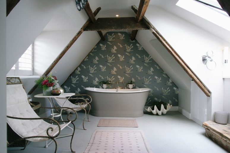 an elegant attic bathroom with a wallpaper statement wall, a grey bathtub, elegant chairs and potted blooms  (Aston Matthews)