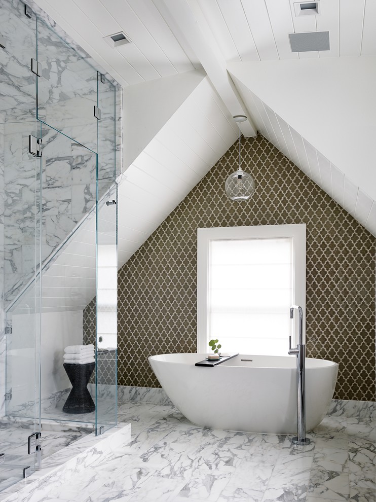 an elegant attic bathroom with marble tiles, an oval tub, a catchy tile statement wall  (Art of Construction Inc)