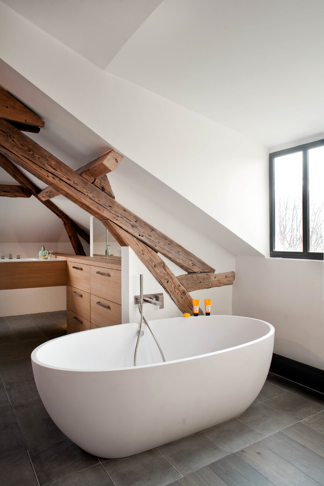 a contemporary meets rustic bathroom with wooden beams, an oval tub and white cabinets  (Olivier Chabaud Architecte)