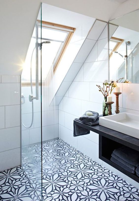 a black and white attic bathroom with mosaic tiles, a shower space with skylights, a floating vanity