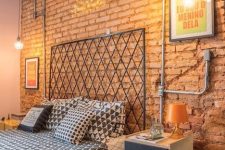 a bold industrial bedroom with red brick walls, exposed pipes, a metal bed, catchy nighstands with casters
