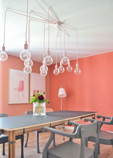 a chic contemporary dining room with a bulb chandelier, a grey dining table and chairs and bright artworks