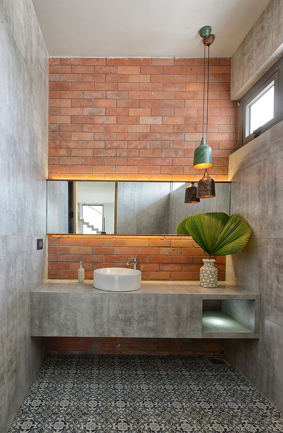 a chic industrial bathroom with concrete walls and a vanity, a brick wall, printed tiles, pendant lamps and some skylights