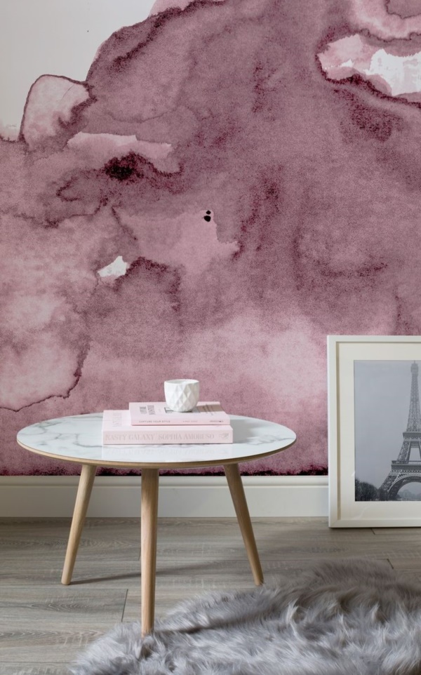 a cool space with a pink watercolor wall, a round table, a grey faux fur rug, an artwork is a stylish and bold nook