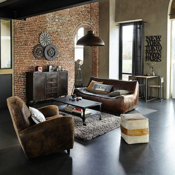 a cozy industrial space done with leather furniture, a brick statement wall, a furry rug and a metal coffee table