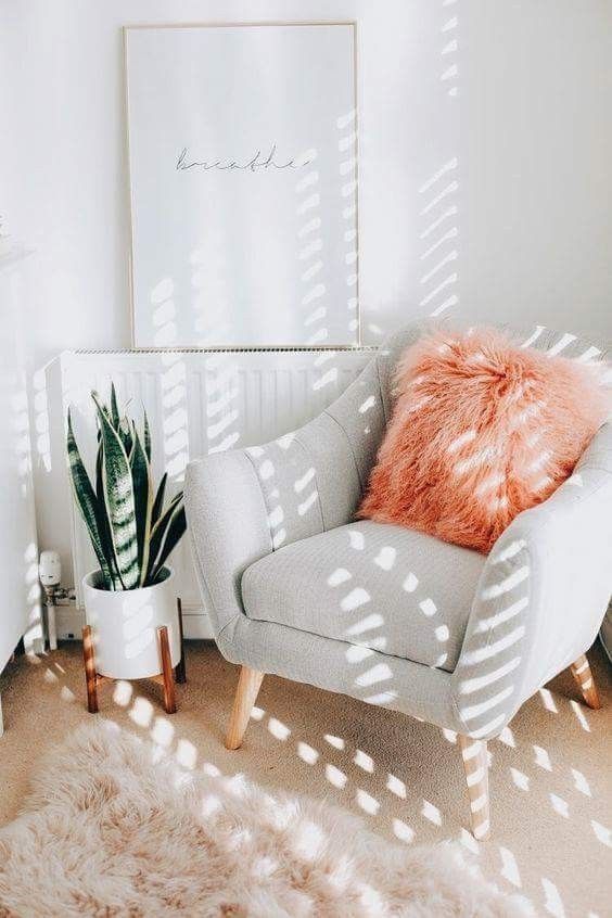 a cozy nook with a dove grey chair, a fluffy coral pillow and a faux fur rug is a cute and fun idea for a contemporary home