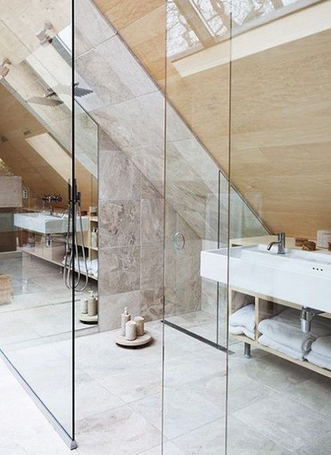 a marble tile and wood attic bathroom with a shower space, many candles and skylights