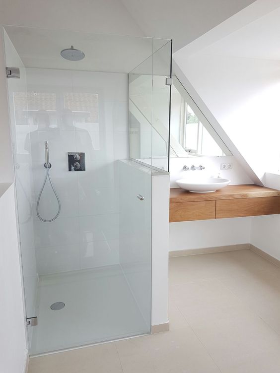 a minimalist attic bathroom with a wooden floating vanity and a white shower