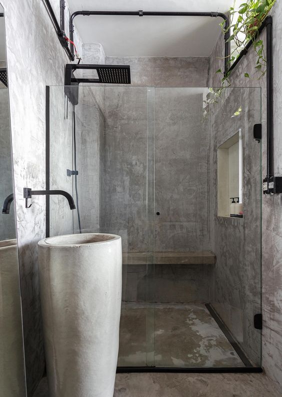 a minimalist industrial bathroom fully clad with concrete, a free-standing sink, black fixtures and potted greenery