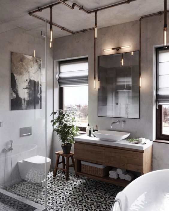 a modern industrial chic bathroom with concrete walls, printed tiles, a wooden vanity, exposed pipe lamps, chic appliances