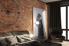 a modern industrial space ith brick walls, a concrete ceiling, an upholstered bed, a statement artwork and unique industrial clock