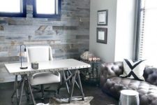 a rustic meets industrial home office with a weathered wooden wall, a metal trestle desk, a leather sofa and a metal stool