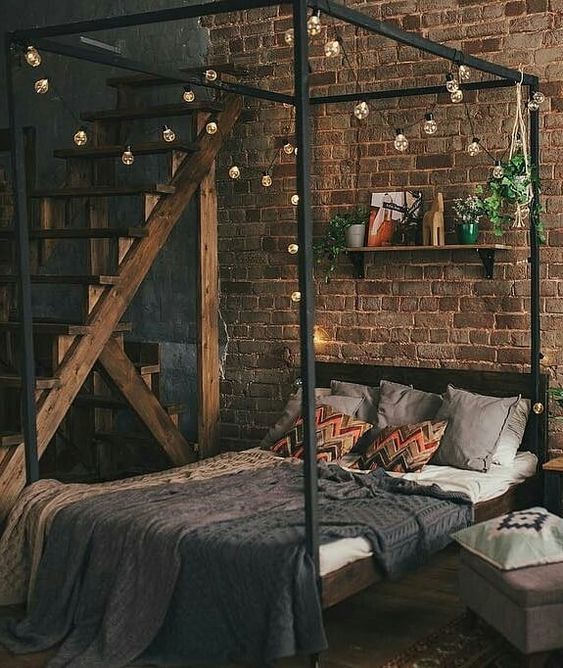 a small and welcoming industrial bedroom with a brick accent wall, a black canopy bed with lights and an open shelf, a wooden ladder