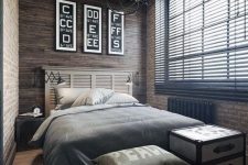 a stylish industrial bedroom clad with wood and brick, with wooden beams and a cool sphere chandelier, a bed with a shutter headboard, neutral bedding and chests for storage