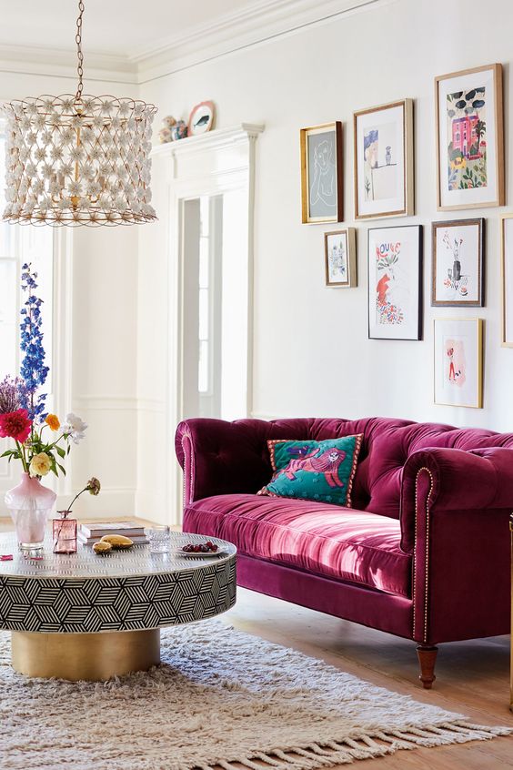 a tufted burgundy sofa is a bold and refined statement in the space and it will work for all the seasons