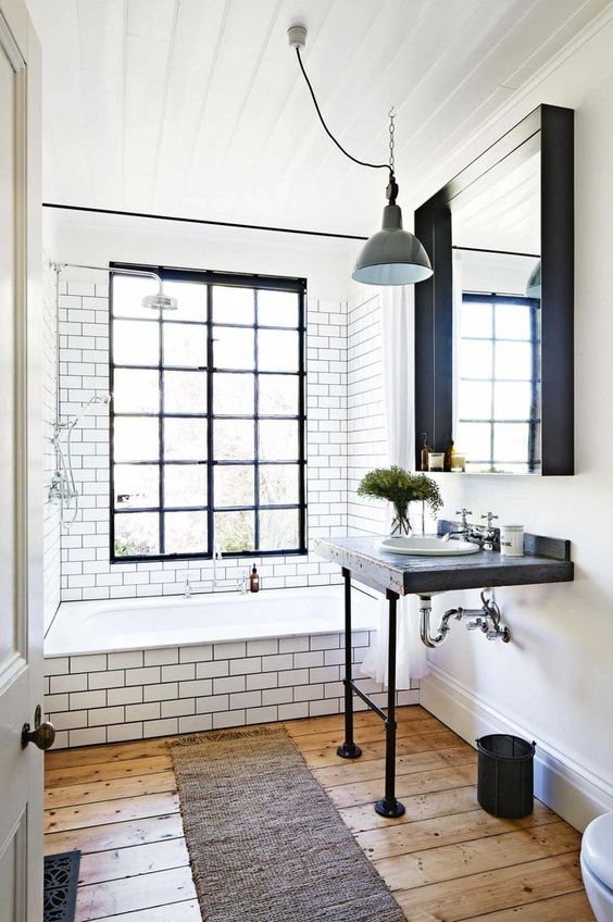 a vintage meets industrial bathroom with white subway tiles, a wooden vanity, a large mirror, pendant lamps