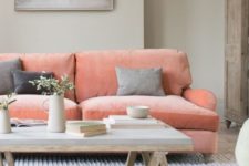 a welcoming living room with dove grey walls, a coral pink sofa, a concrete coffee table, an artwork and a wooden clsoet