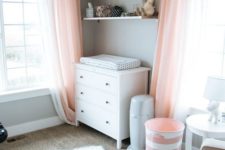 an airy dove grey and light coral nursery, with white furniture and a rug, with coral textiles and greys
