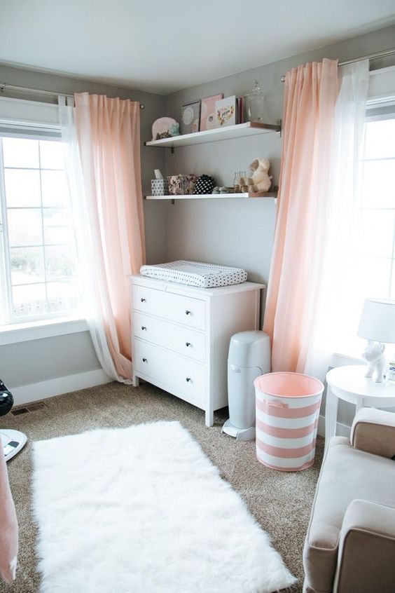 an airy dove grey and light coral nursery, with white furniture and a rug, with coral textiles and greys