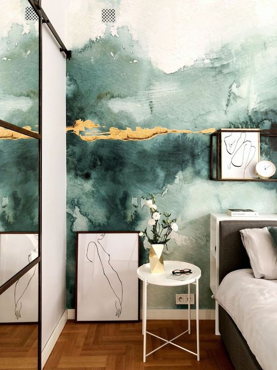 an eye-catchy bedroom with a green watercolor wall with touches of gold, a bed with neutral bedding, artwork, a side table