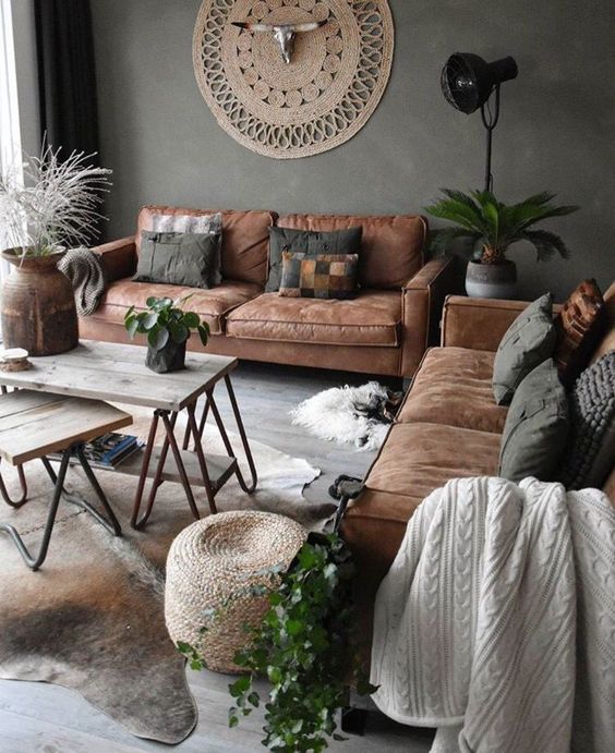 an industrial boho living room with leather sofas, potted plants, hairpin leg coffee tables and jute decor
