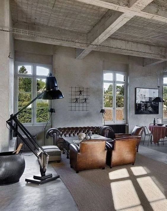 an industrial living room with retro touches, a metal floor lamp, leather furniture and concrete walls and floor