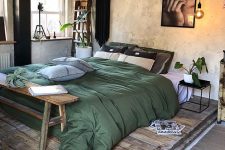 an industrial sleeping space with shabby walls, a pallet platform with a bed, a wooden bench, some pretty plants and textiles