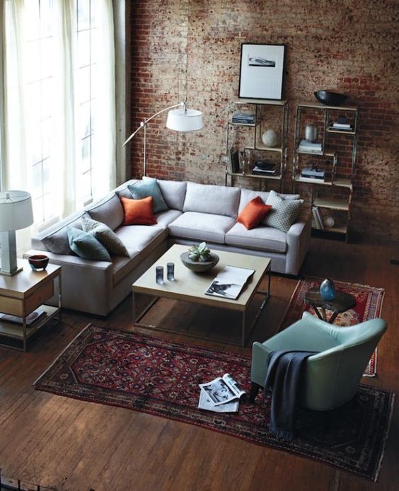brick walls, rich-colored wood floors, an industrial piping open shelving unit and a metal and wood coffee table