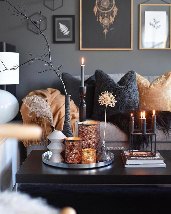 Nordic fall living room done in grey, black and orange, with candles, catchy lanterns and a gallery wall plus branches