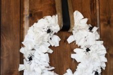 a Halloween wreath covered with white fabric stripes, with black spiders and a burlap and black ribbon is simple and cool