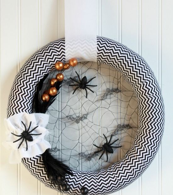 a black and white Halloween chevron wreath with spider webs, spiders and feathers plus oversized beads is a cool idea to decorate your front door