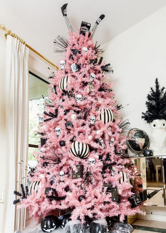 a black, pink and white Halloween tree with large ornaments, skulls, witches' legs and bottle cleaners