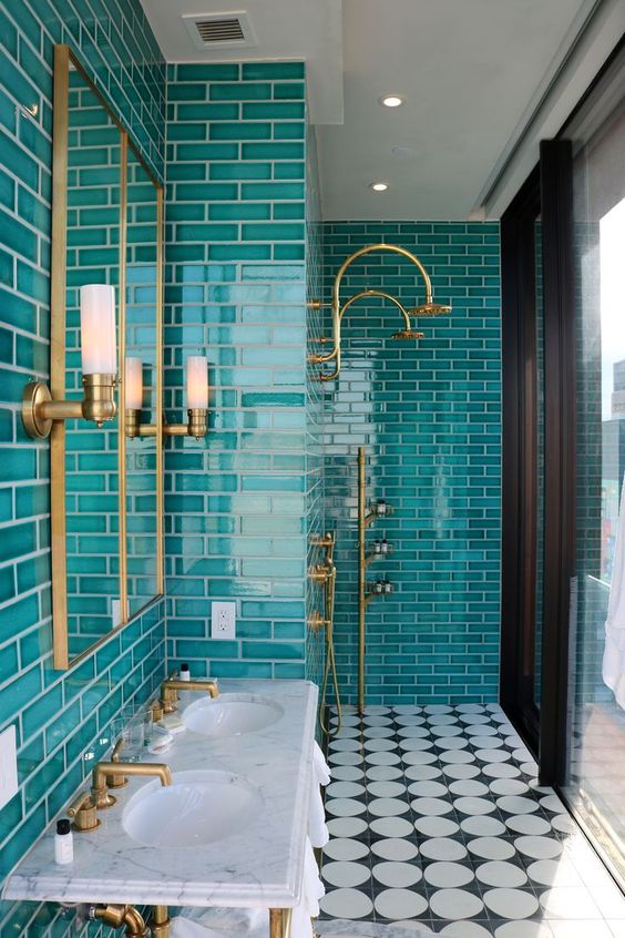 a bright bathroom clad with turquoise tiles, with gold fixtures and a mirror in a gold frame is a bold and catchy space