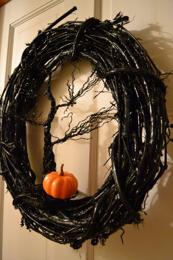 a catchy Halloween wreath of black vine, a glitter tree and a small pumpkin is amazing for decorating your front door