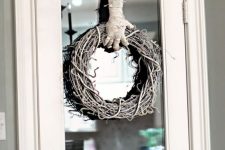 a catchy whitewashed vine wreath with a mummy hand holding it is a very creative and out of the box idea for Halloween