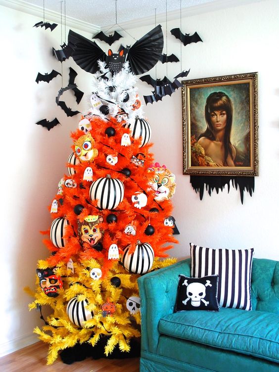 a color block Halloween tree in orange and yellow, with striped oversized ornaments, black ornaments and mini ghosts and bats over it