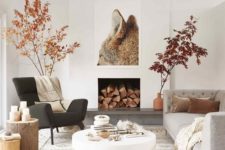 a fall Scandinavian living room with branches with leaves, faux fur, candles on tree stumps and a fox artwork