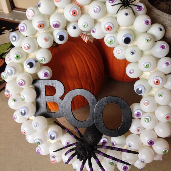 a fun Halloween wreath of googly eyes, a black spider and black letters is a gorgeous idea for styling for Halloween