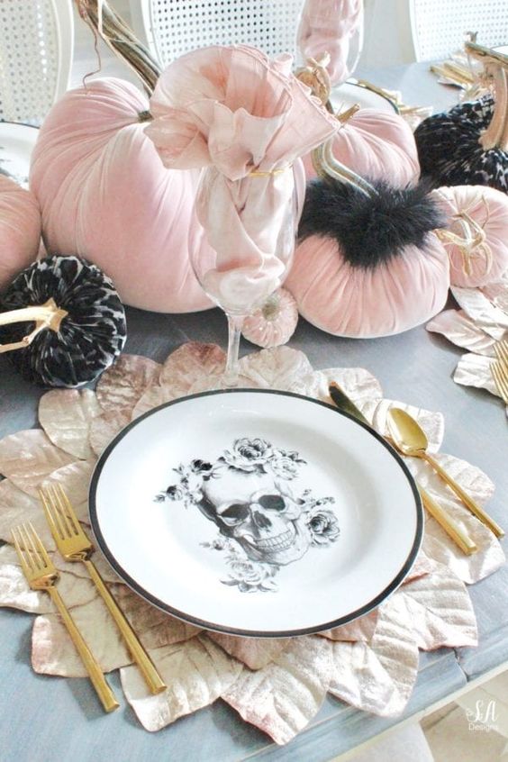 a glam Halloween tablescape with pink velvet pumpkins, black fur, leaf placemats, skull plates and gold cutlery