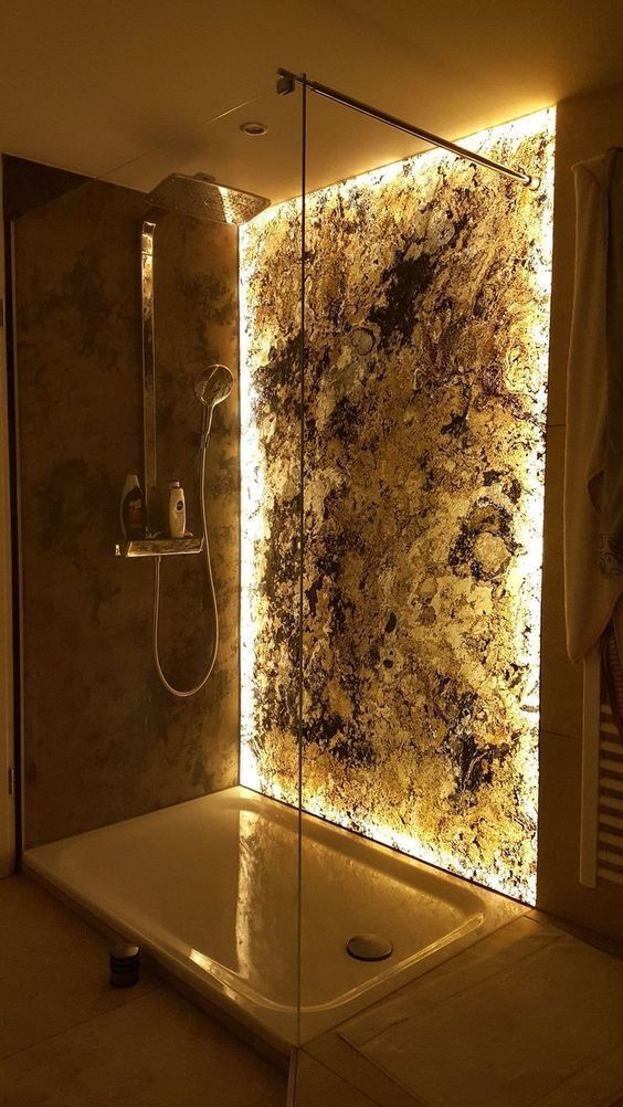 a gorgeous shower space with a lit up stone accent wall and modern fixtures plus a rain shower - this accent wall just wows