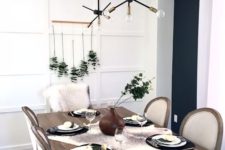 a laconic Thanksgiving tablescape with a eucalyptus arrangement, little white pumpkins, blakc plates and a fau fur runner