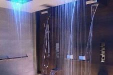 a luxurious shower space with waterfalls and waterfall and rain shower heads with regulated color lights
