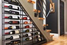 a metal shelf attached under  the staircase is a cool and bold idea that takes yoru wine on display