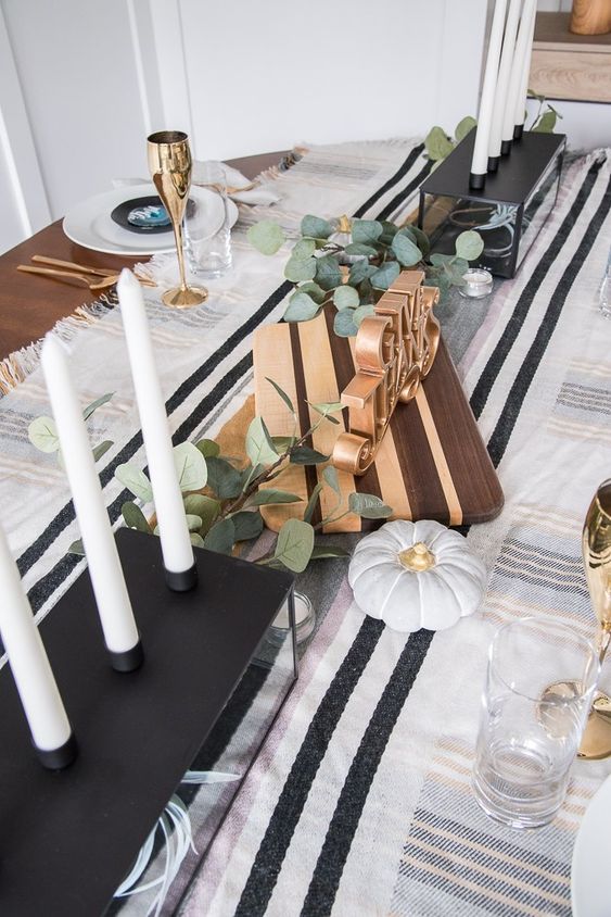 a modern classic Thanksgiving tablescape in black and white, with tall candles, eucalyptus, faux pumpkins