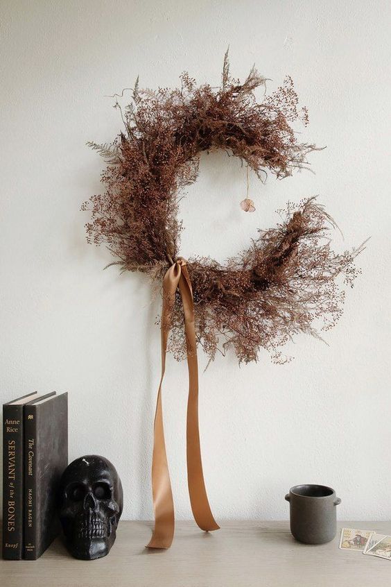 a moody rust-colored branch crescent moon wreath with rust silk ribbons is an out of the box and fresh idea for Halloween