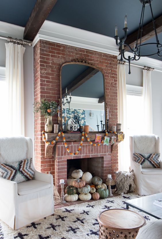 A natural pumpkin stack in the fireplace decorated with fall colored garlanfs and greenery
