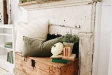 a neutral and relaxed fall fireplace with pillows and greenery, white pumpkins and cocnrete pots for a vintage feel