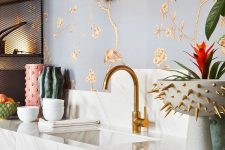 a refined kitchen with gold floral wallpaper, gold sconces, gold fixtures and a bowl with gold spikes is cool